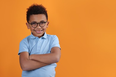 Photo of Cute African-American boy with glasses on orange background. Space for text