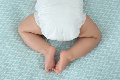 Photo of Cute little baby in diaper on bed, above view