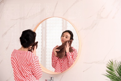 Photo of Young woman with towel near mirror in bathroom