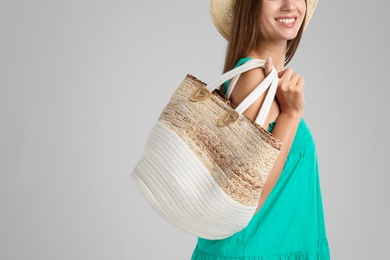 Young woman with stylish straw bag on light grey background, closeup. Space for text