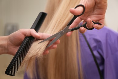 Photo of Stylist cutting hair of client in professional salon, closeup