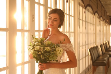Gorgeous bride in beautiful wedding dress with bouquet in restaurant