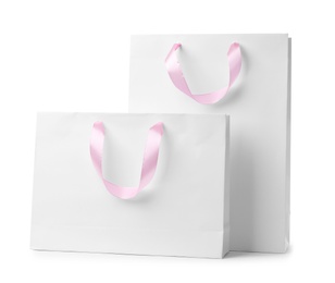 Paper shopping bags with ribbon handles on white background. Mockup for design