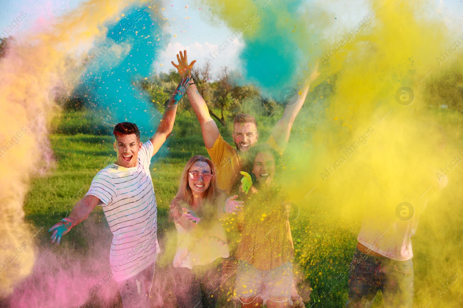 Photo of Happy friends having fun with colorful powder dyes outdoors. Holi festival celebration