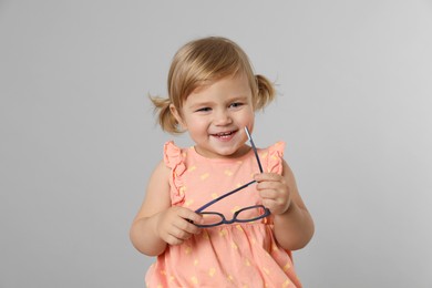 Photo of Cute little girl with glasses on light grey background