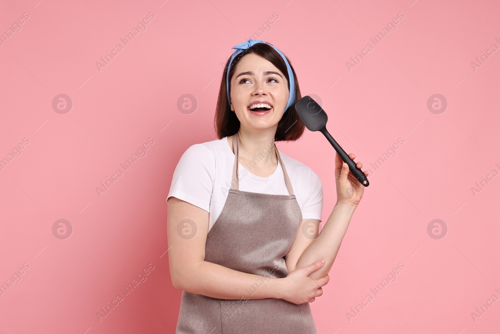 Photo of Happy confectioner with spatula on pink background