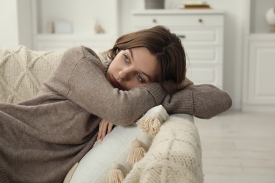 Photo of Sad young woman lying on sofa at home