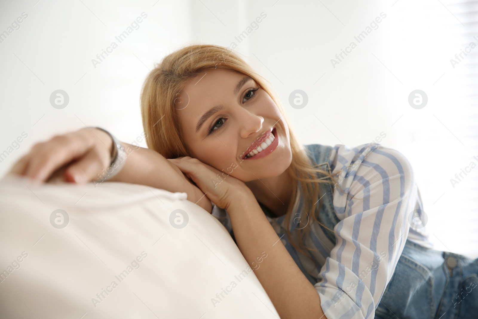 Photo of Young woman relaxing on couch near window at home