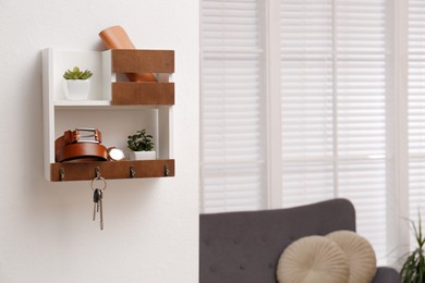 Hallway interior with stylish accessories and wooden hanger for keys on white wall