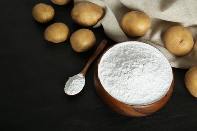 Starch and fresh raw potatoes on black table, above view