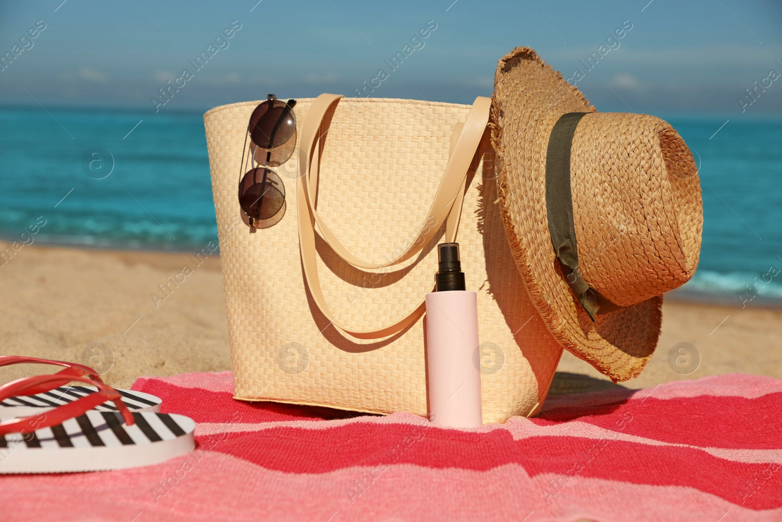 Photo of Straw hat, bag and other beach items on sandy seashore