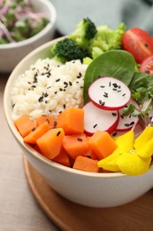 Photo of Bowl with many different vegetables and rice on wooden table, closeup. Vegan diet