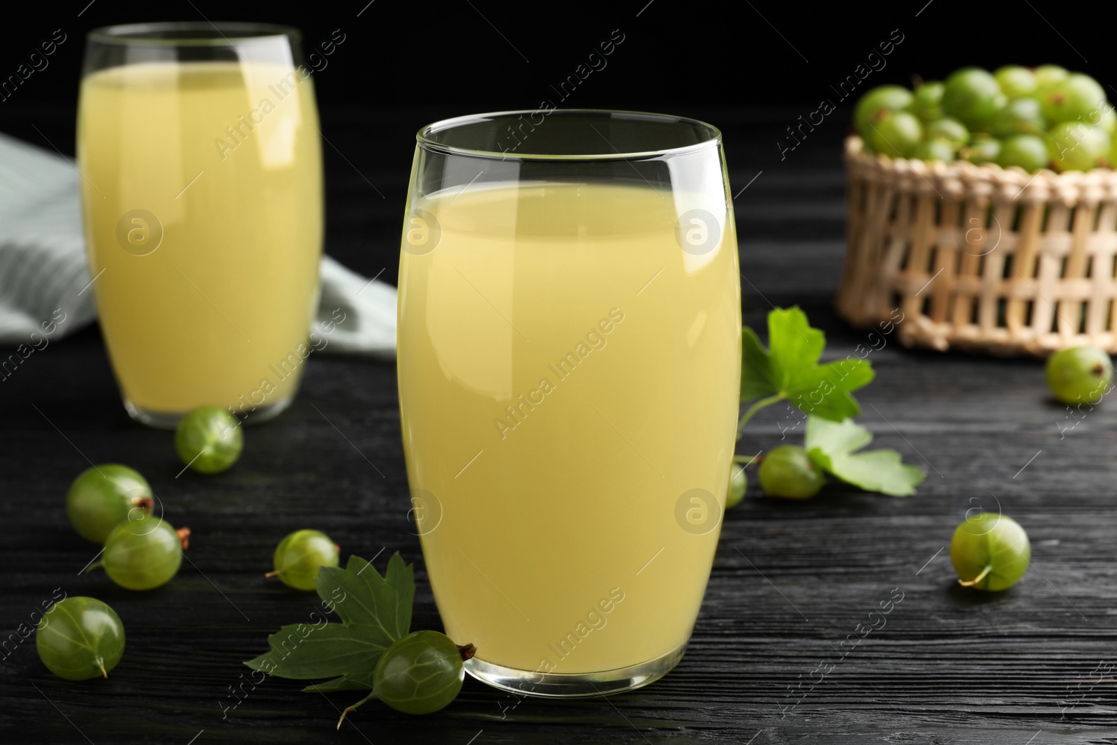 Photo of Tasty gooseberry juice on black wooden table, closeup