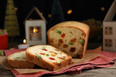 Delicious cake with candied fruits and Christmas decor on wooden table