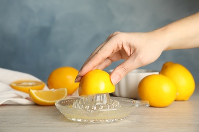 Woman squeezing lemon juice at wooden table, closeup