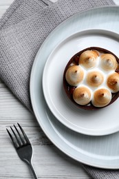 Photo of Delicious salted caramel chocolate tart with meringue served on white wooden table, flat lay