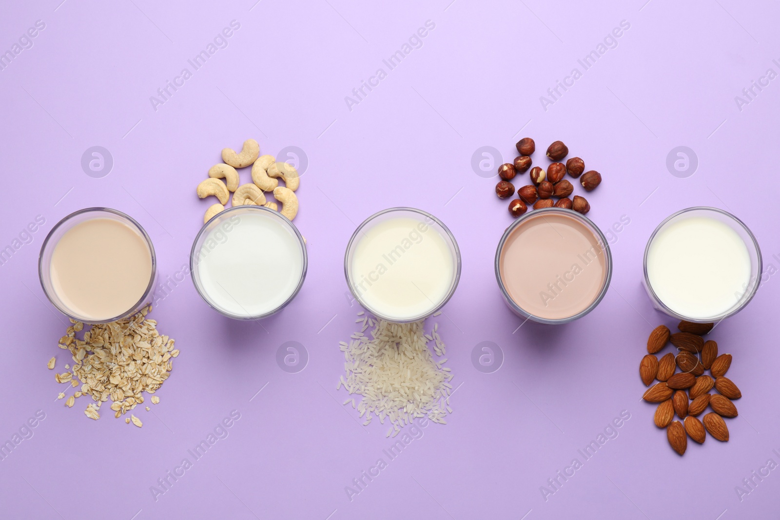 Photo of Different vegan milks and ingredients on violet background, flat lay