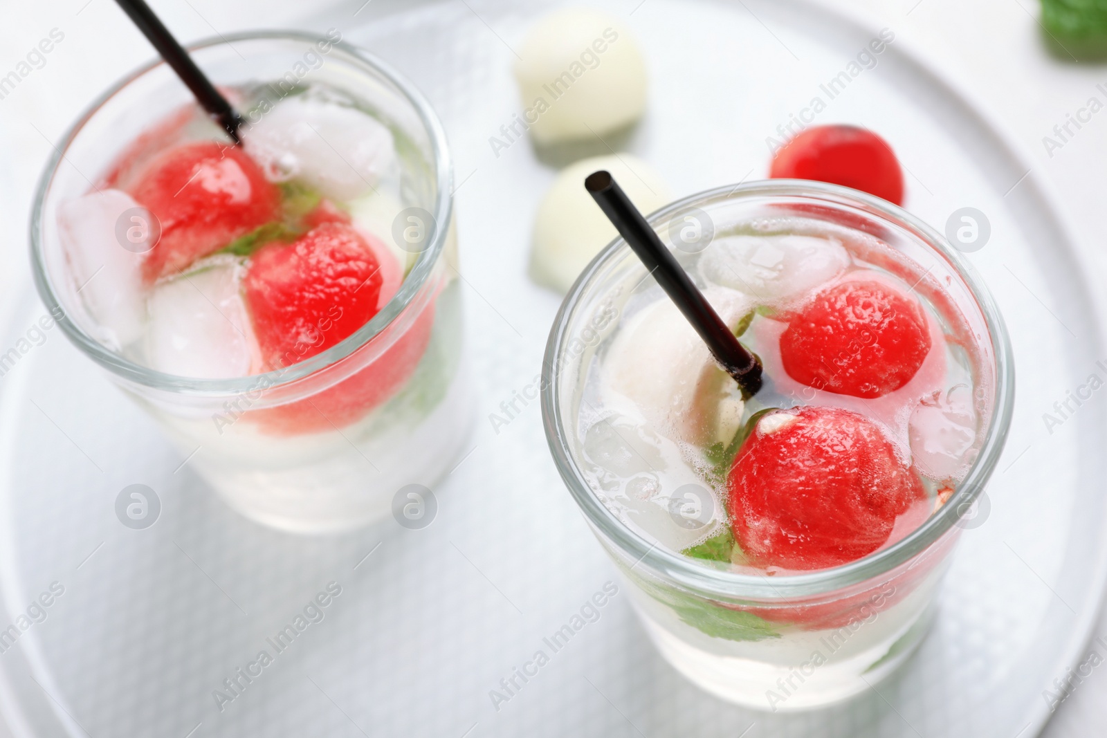 Photo of Glasses with tasty melon and watermelon ball drinks on plate, closeup