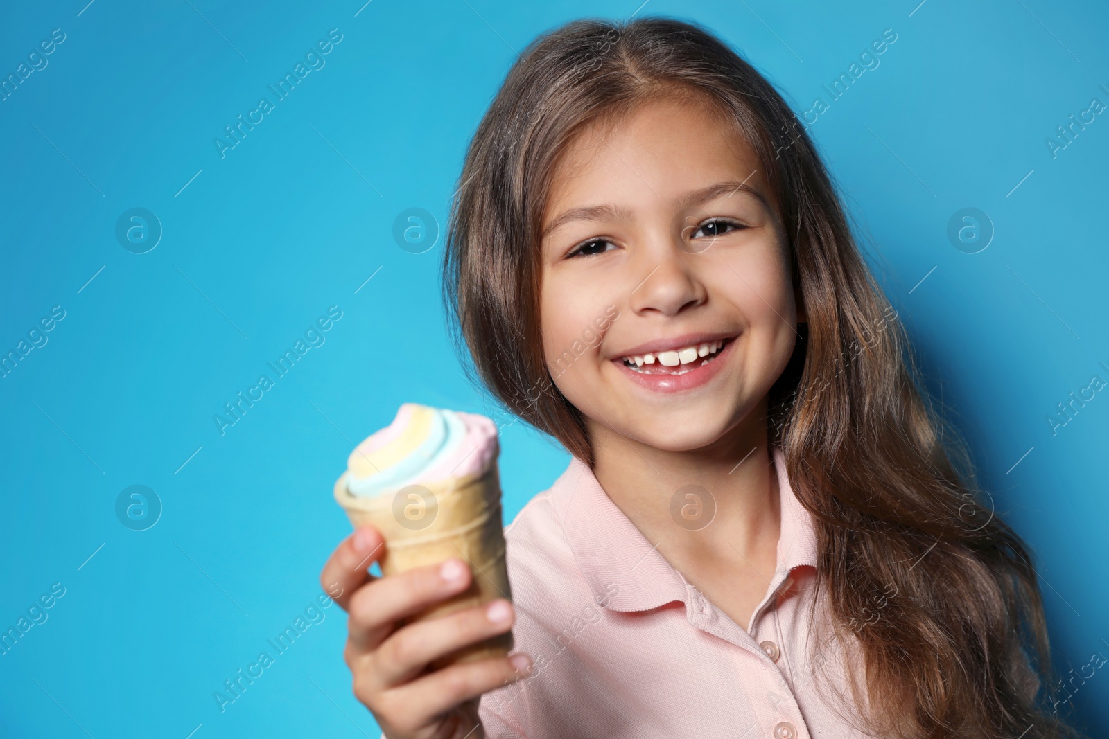 Photo of Cute little girl with delicious ice cream against color background, space for text