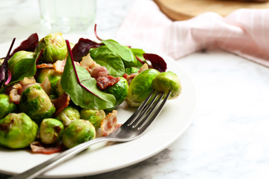 Photo of Delicious Brussels sprouts with bacon on table, closeup
