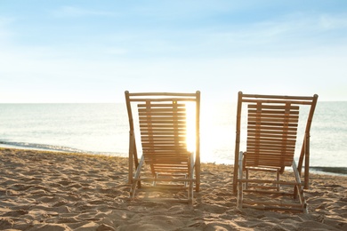 Wooden deck chairs on sandy beach. Summer vacation