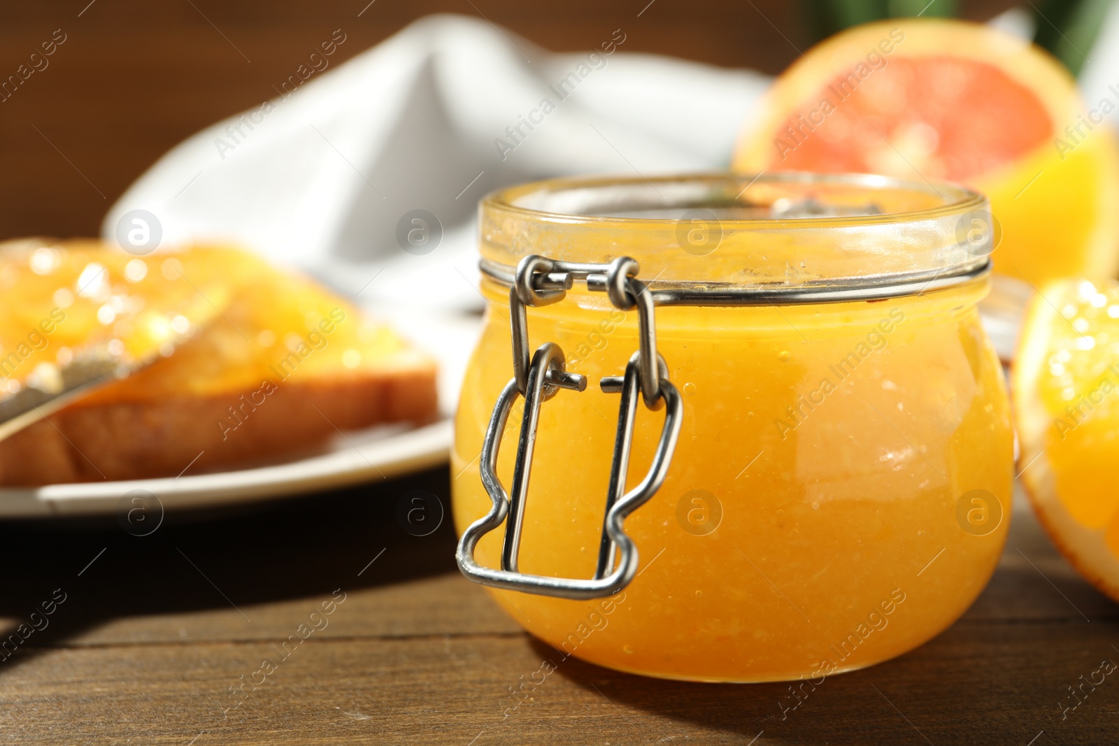Photo of Delicious orange marmalade on wooden table, closeup. Space for text