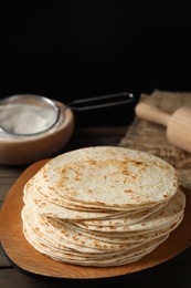 Photo of Many tasty homemade tortillas and rolling pin on wooden table