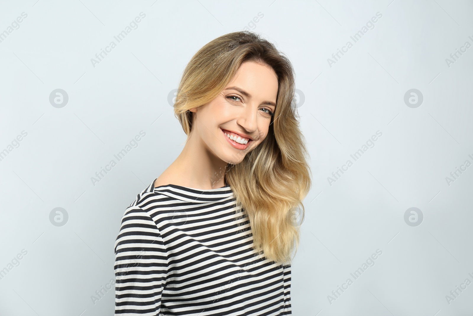 Photo of Portrait of happy young woman with beautiful blonde hair and charming smile on light background