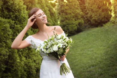 Gorgeous bride in beautiful wedding dress with bouquet outdoors