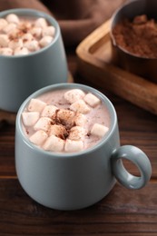 Photo of Cups of aromatic hot chocolate with marshmallows and cocoa powder on table, closeup