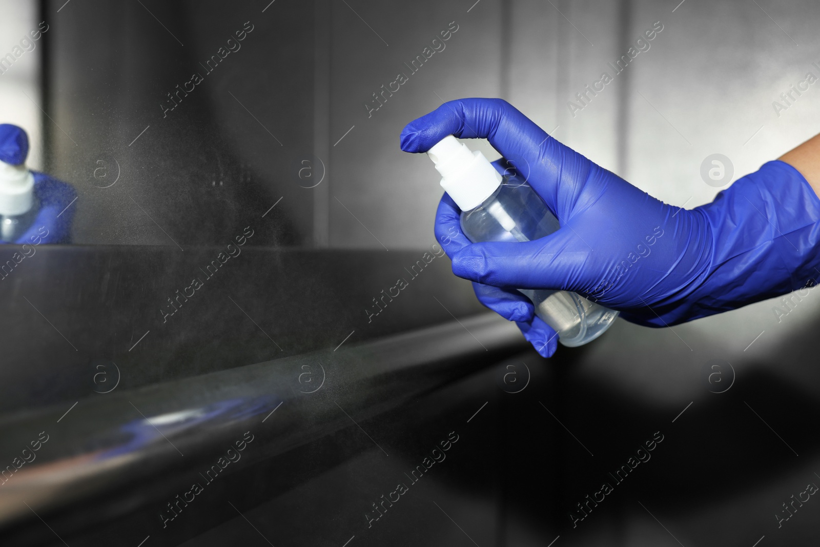 Photo of Woman cleaning elevator`s handrails with detergent, closeup