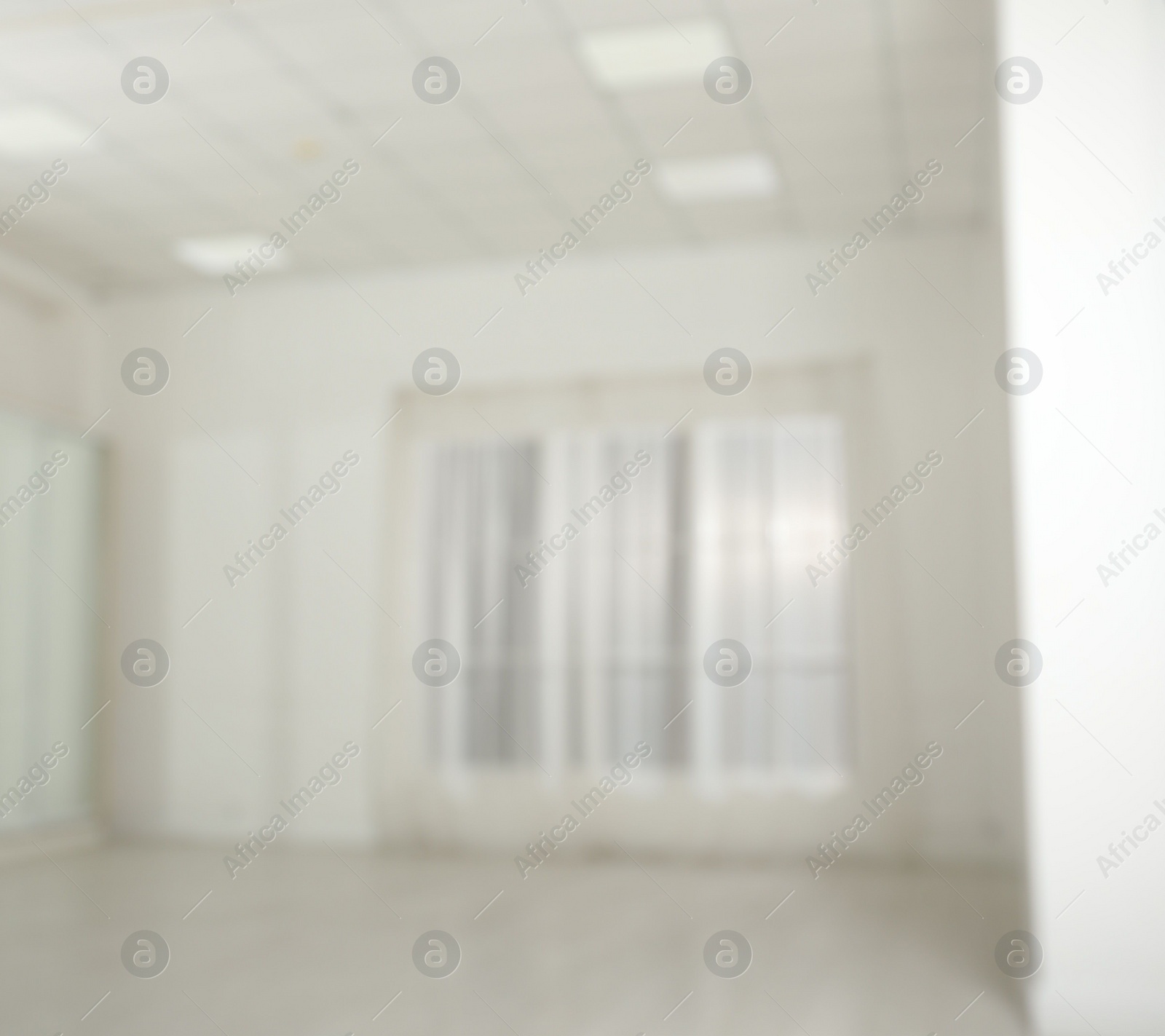 Photo of Empty room with white walls and large window, blurred view