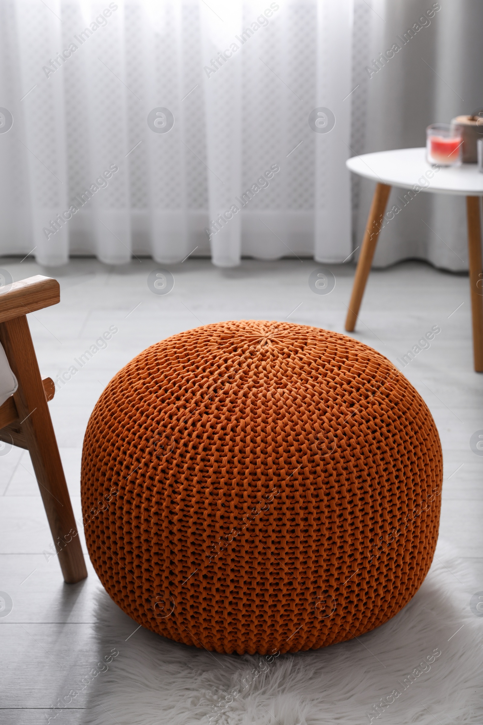 Photo of Stylish knitted pouf on floor in room. Interior design