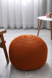 Stylish knitted pouf on floor in room. Interior design