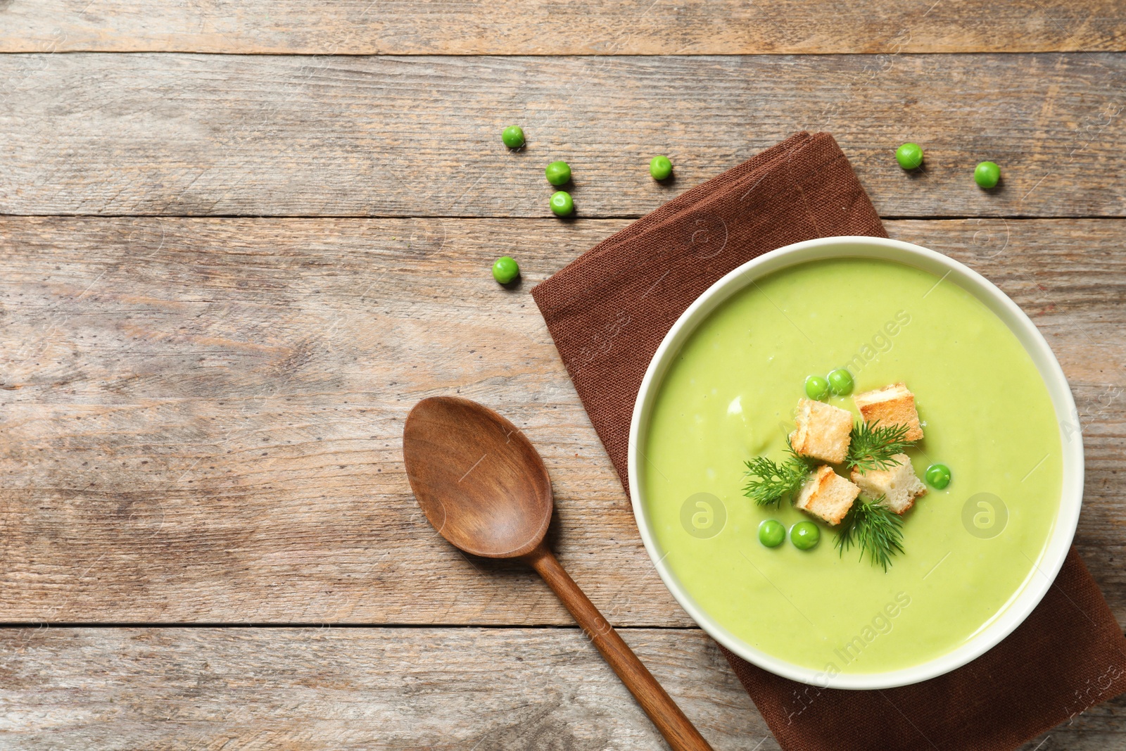 Photo of Fresh vegetable detox soup made of green peas with croutons in dish served on table, top view. Space for text