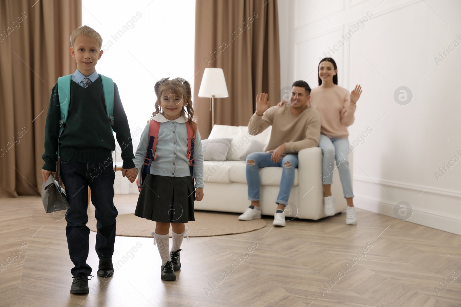 Photo of Kids with backpacks and their parents on sofa at home. Getting ready for school