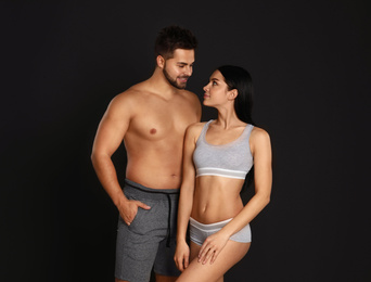 Photo of Young couple in grey sportive underwear on black background