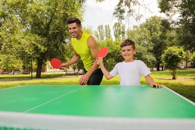 Photo of Happy man with his son playing ping pong in park