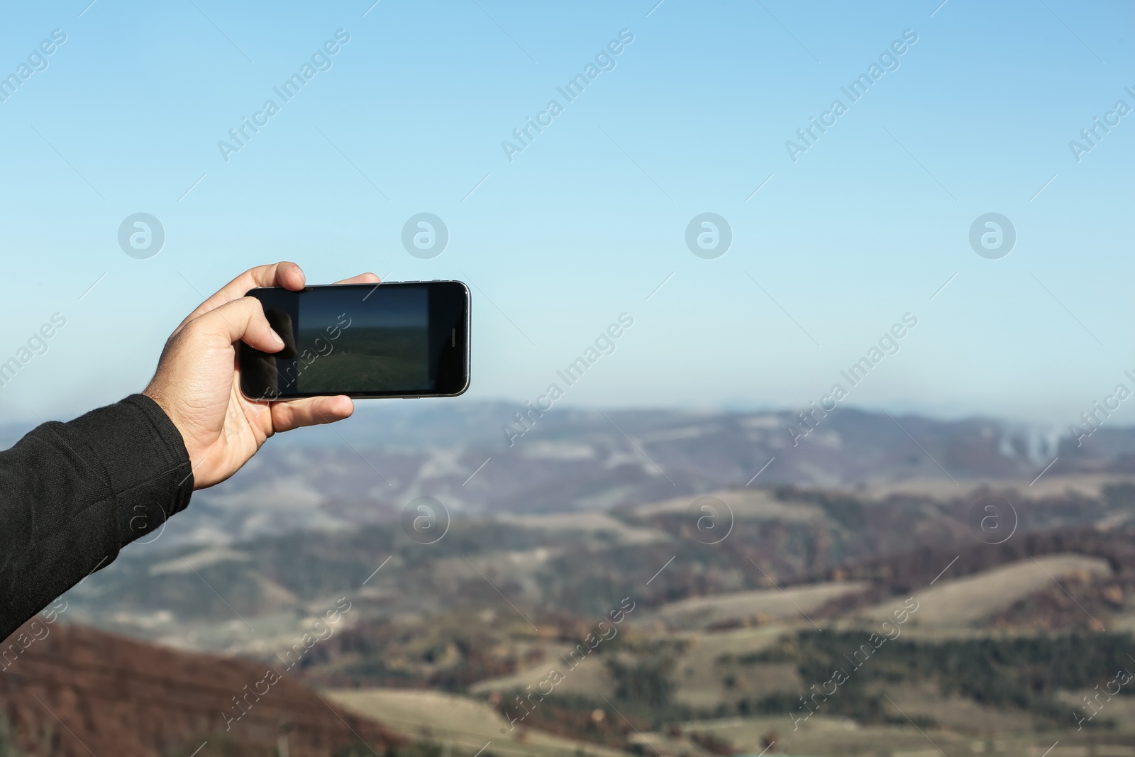 Photo of Man taking photo of beautiful mountain landscape with smartphone