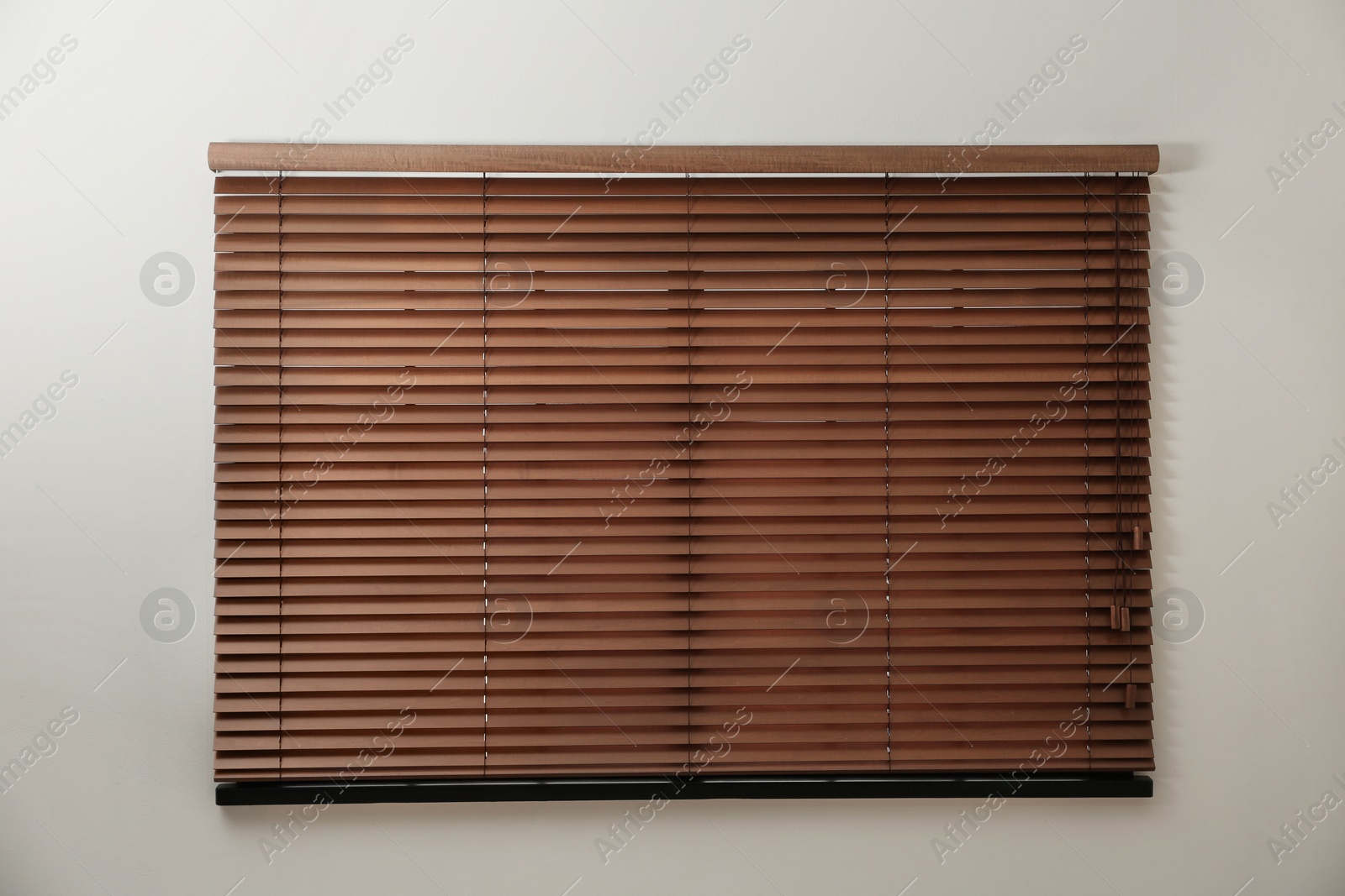 Photo of Modern window with closed stylish wooden blinds indoors. Space for text