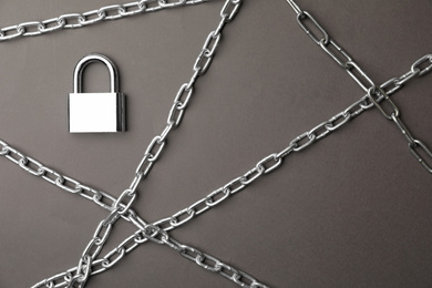 Photo of Steel padlock and chains on grey background, flat lay. Safety concept