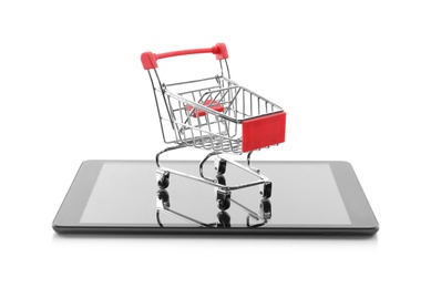 Photo of Internet shopping. Small cart and modern tablet on white background