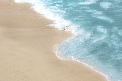 Photo of Beautiful blue wave with sea foam on sandy beach