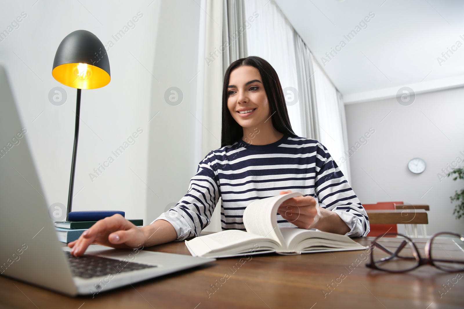 Photo of Young woman with laptop studying at table in library