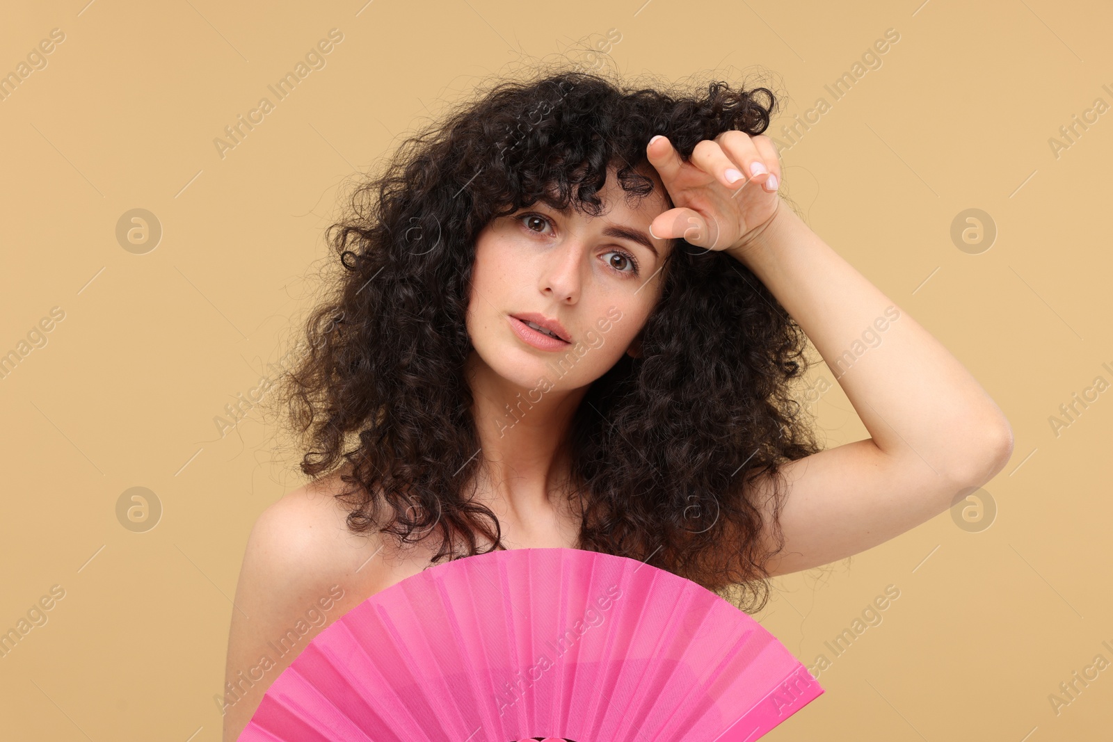 Photo of Woman with hand fan suffering from heat on beige background