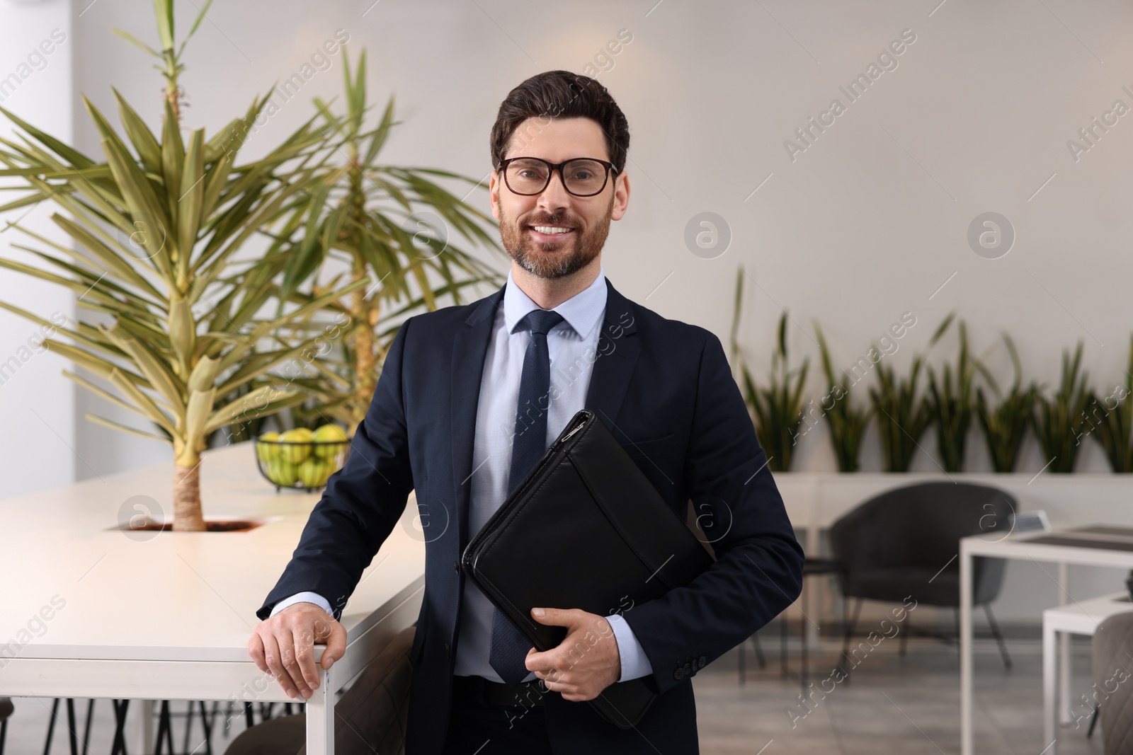 Photo of Happy real estate agent with leather portfolio in office