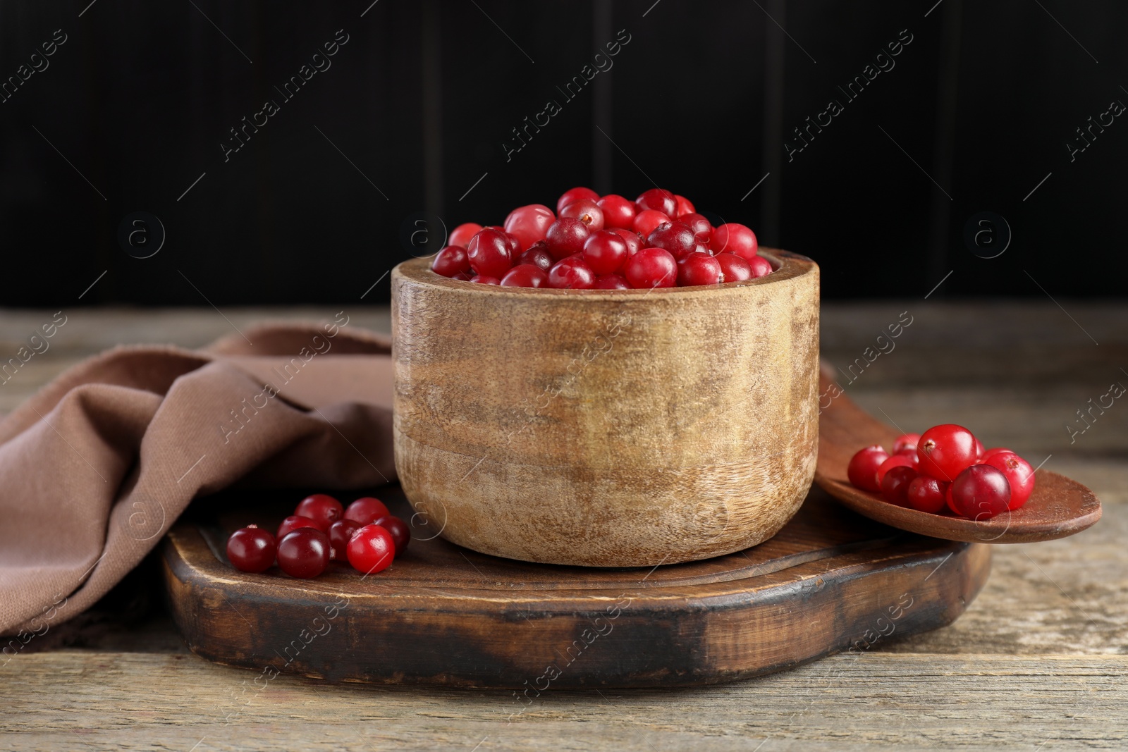 Photo of Ripe cranberries in bowl on wooden table