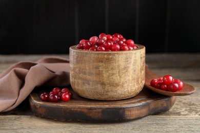 Photo of Ripe cranberries in bowl on wooden table