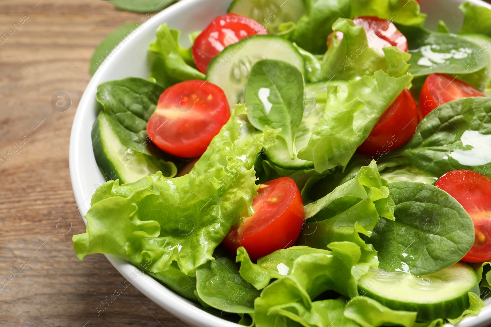 Photo of Delicious vegetable salad on wooden table, closeup