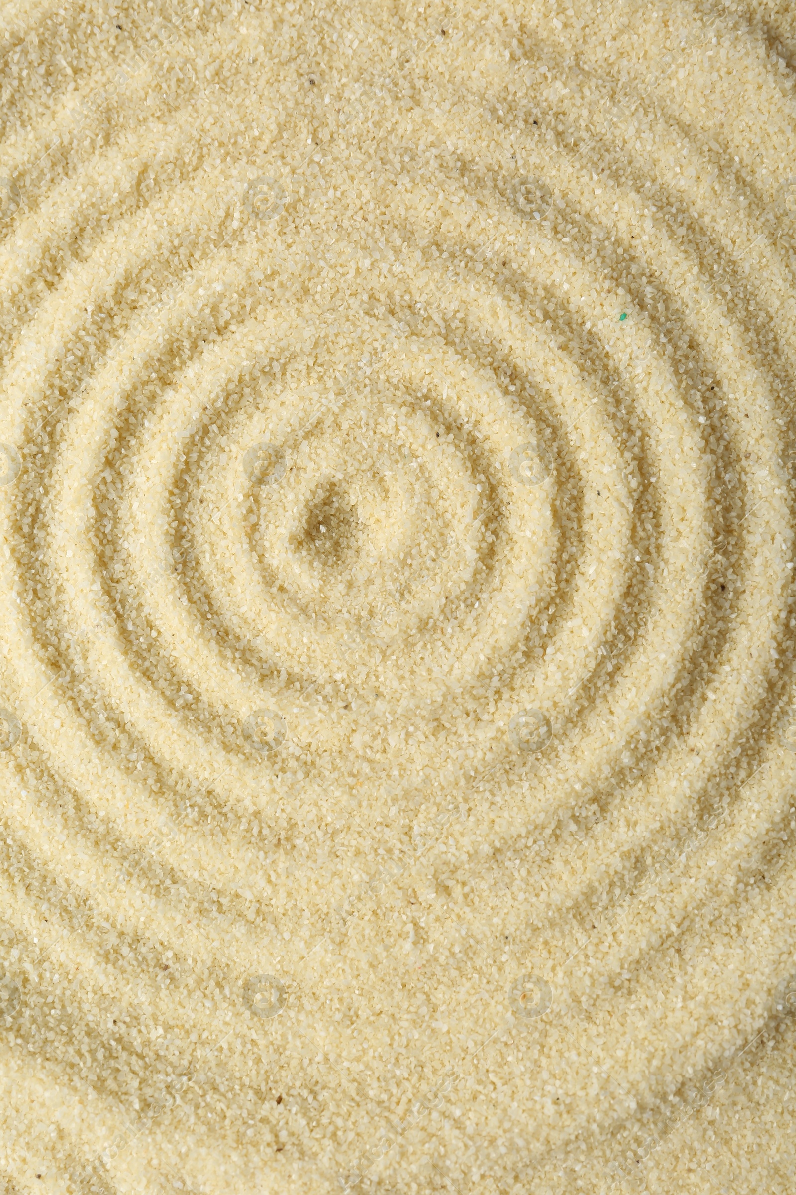 Photo of Zen rock garden. Circle pattern on beige sand, top view